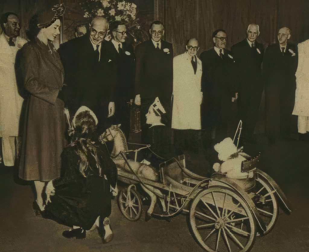 J. Lyons & Co. Management presents Princess Elizabeth with a toy pony and gig for Prince Charles and Princess Anne dressed as a Nippy at Cadby Hall in 1951