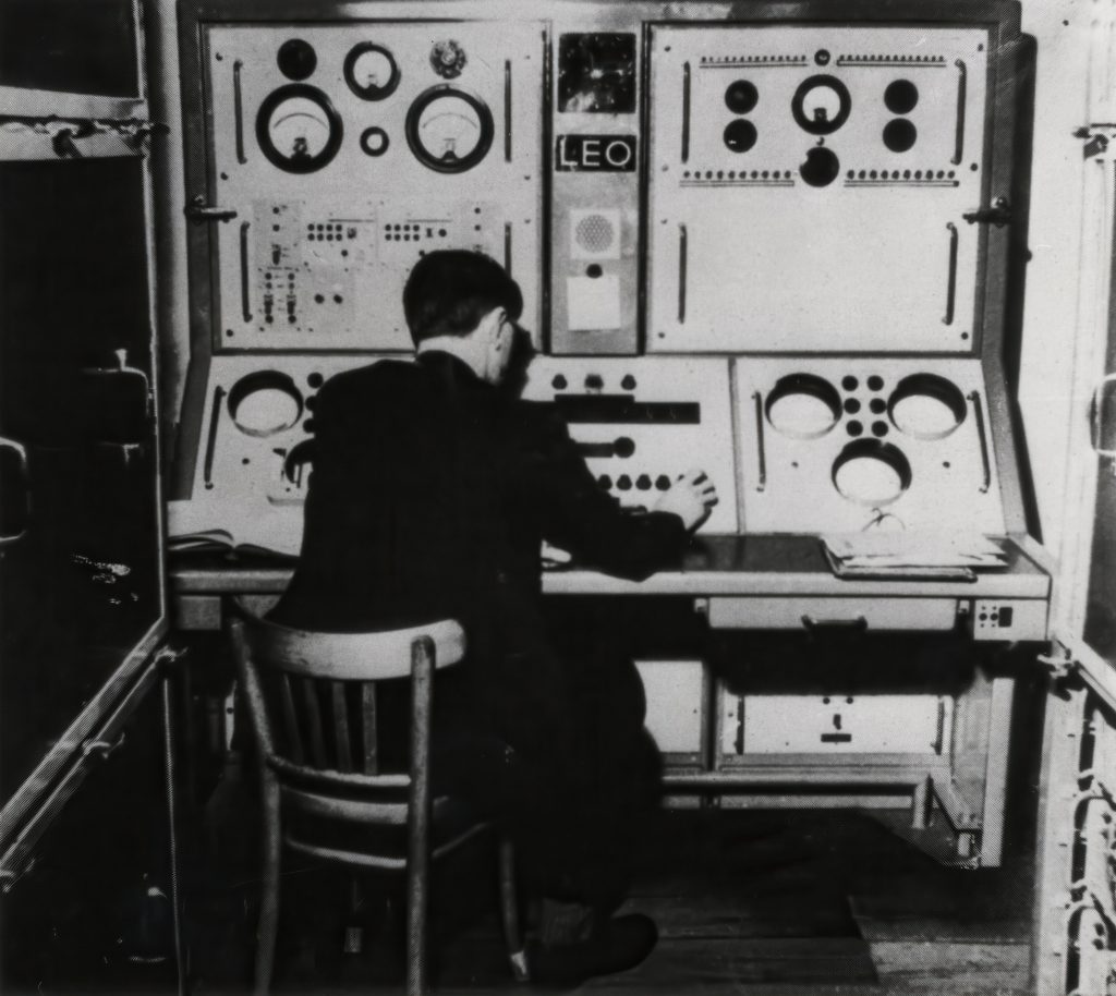 View of the engineer's console of LEO and believed to be Dr. J. Pinkerton operating the computer